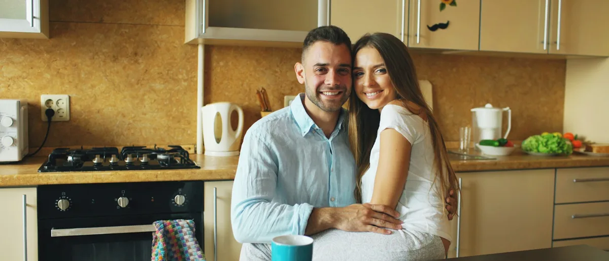 A couple smiling together in a bright modern kitchen