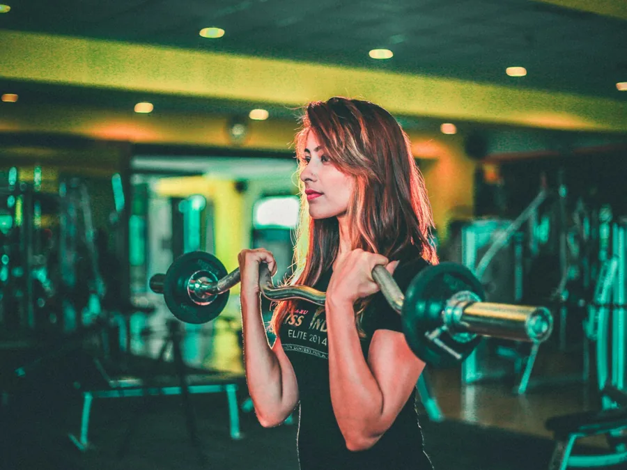 A woman lifting a barbell in a gym